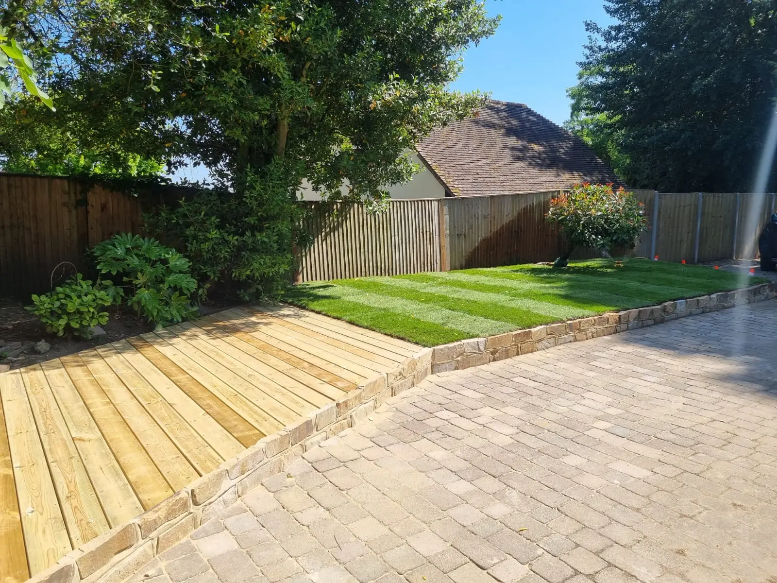 Wood deck and brick patio with striped lawn