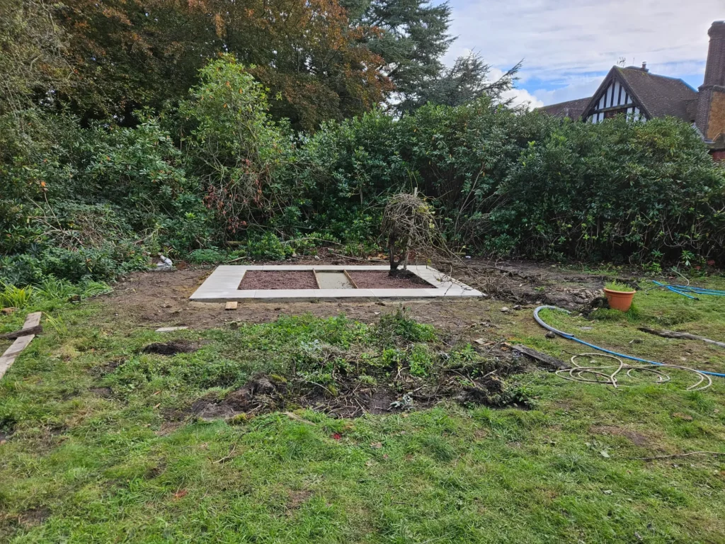 Garden area with a newly constructed square base set within surrounding soil and planting beds.