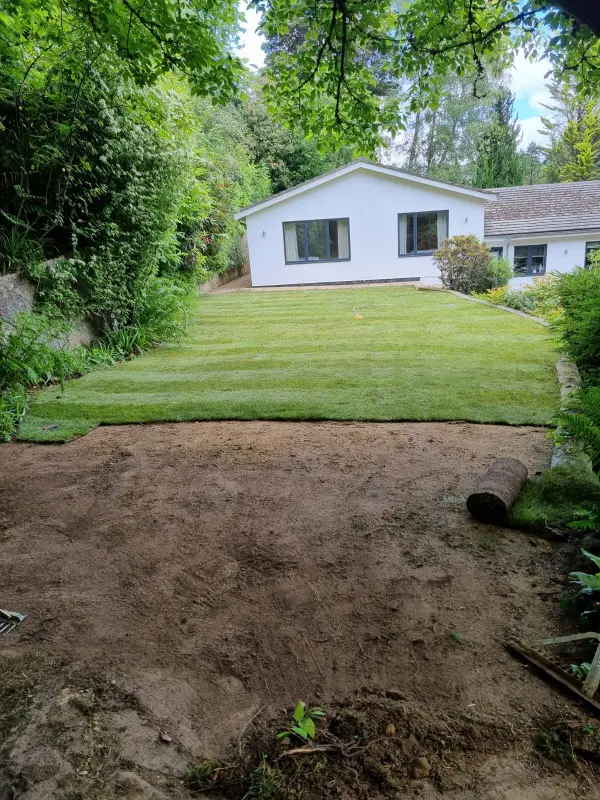 Garden area with exposed soil prepared for turf installation in front of a residential property.