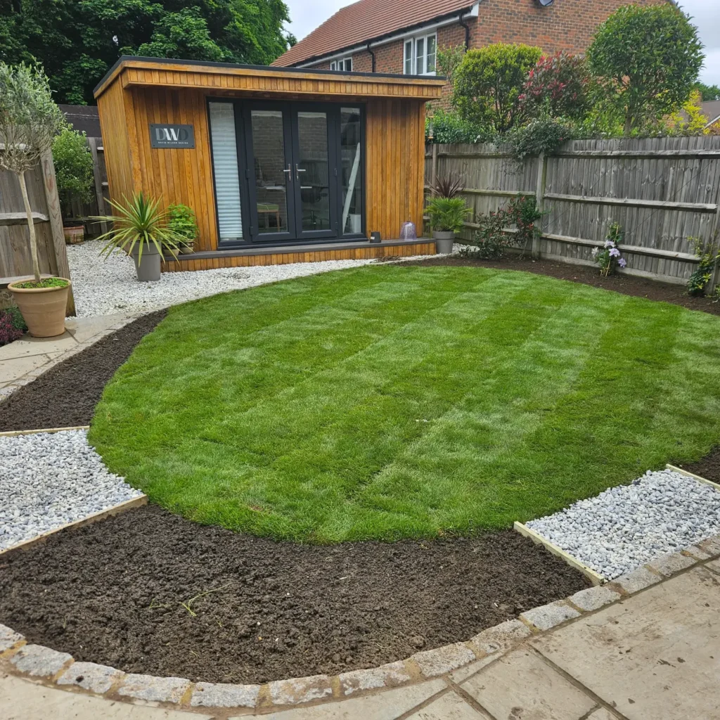Newly laid turf forming a curved lawn bordered by fresh soil and gravel pathways.