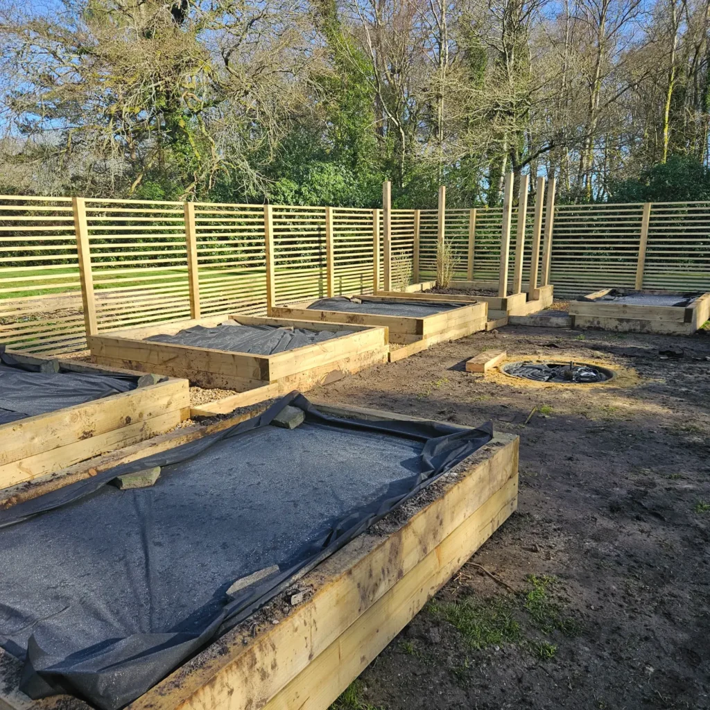 Timber raised planter beds under construction on a prepared soil base.