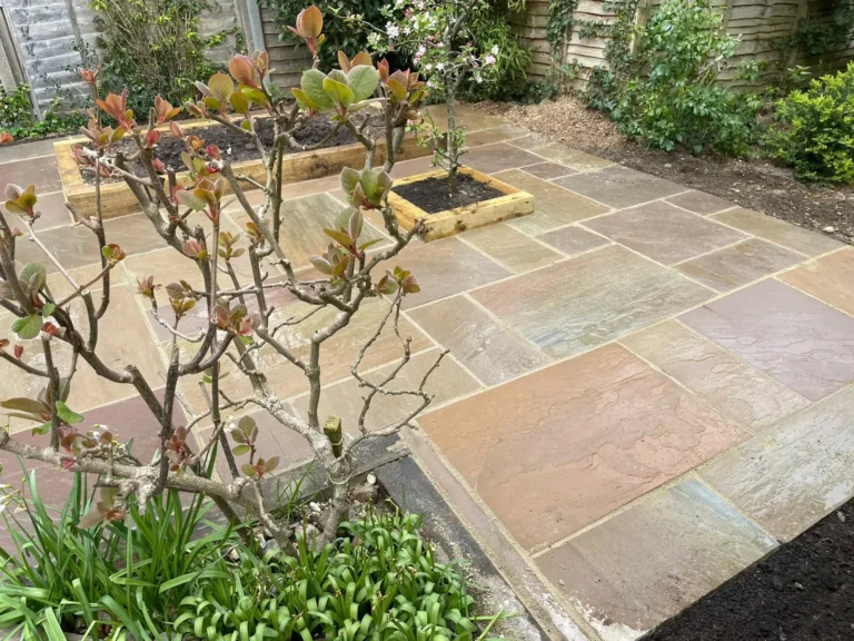 Newly installed sandstone patio with neat edging and integrated planting beds.