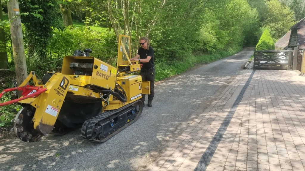 Operative using a stump grinding machine on a roadside verge.